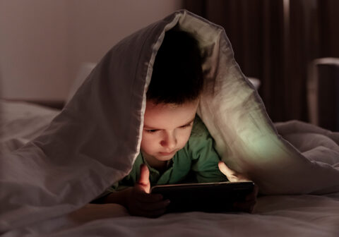 How to help prevent gaming addiction in children boy playing with tablet in bed