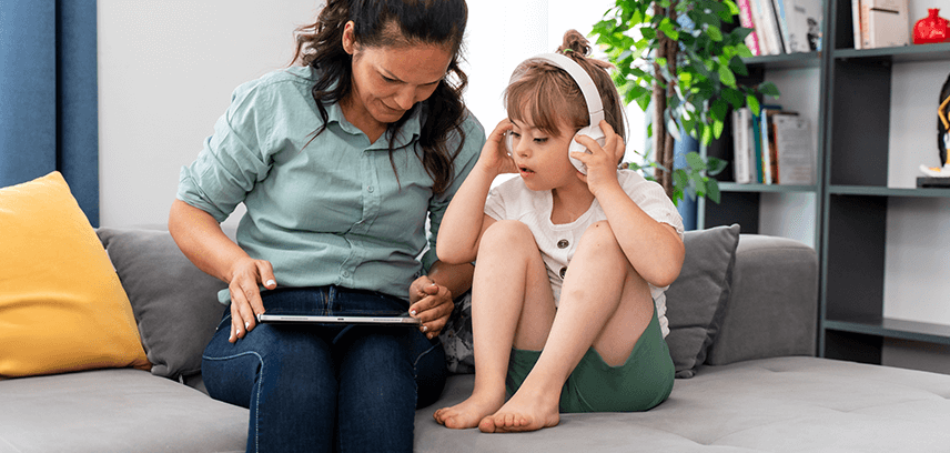 2025-03-Blog_IsSpotifySafeForKids_InsideImage Mother helping daughter set parental controls on Spotify music streaming on iPad